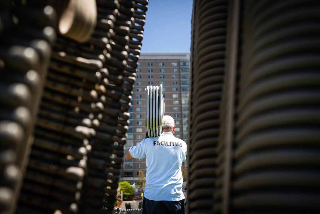 Photo: A picture of a man carrying a stack of chairs amidst many other stacks