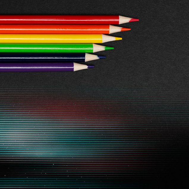 Photo: Pencils in row made of rainbow flag colors symbolizing LGBT movement on black background.
