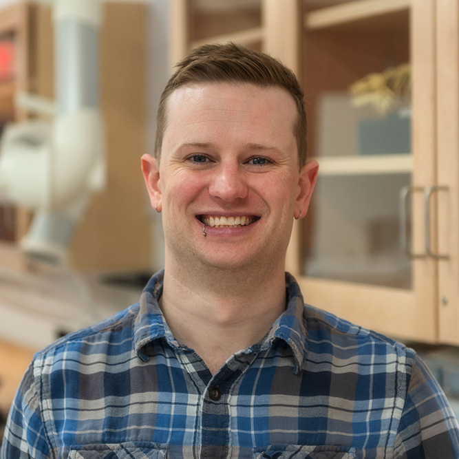 Photo: A formal headshot portrait of a man wearing a plaid formal shirt