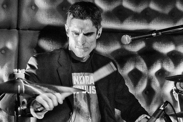 Photo: A black and white picture of Gareth Dylan Smith, a CFA professor, playing the drums on stage