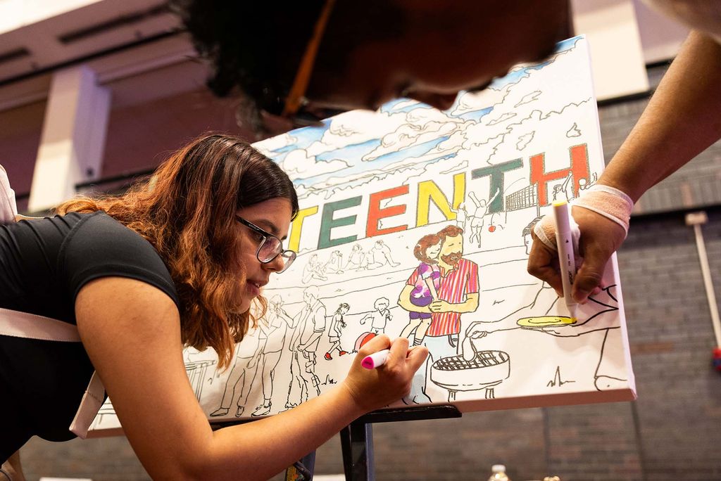 Photo: a picture of students coloring in a "Juneteenth" banner