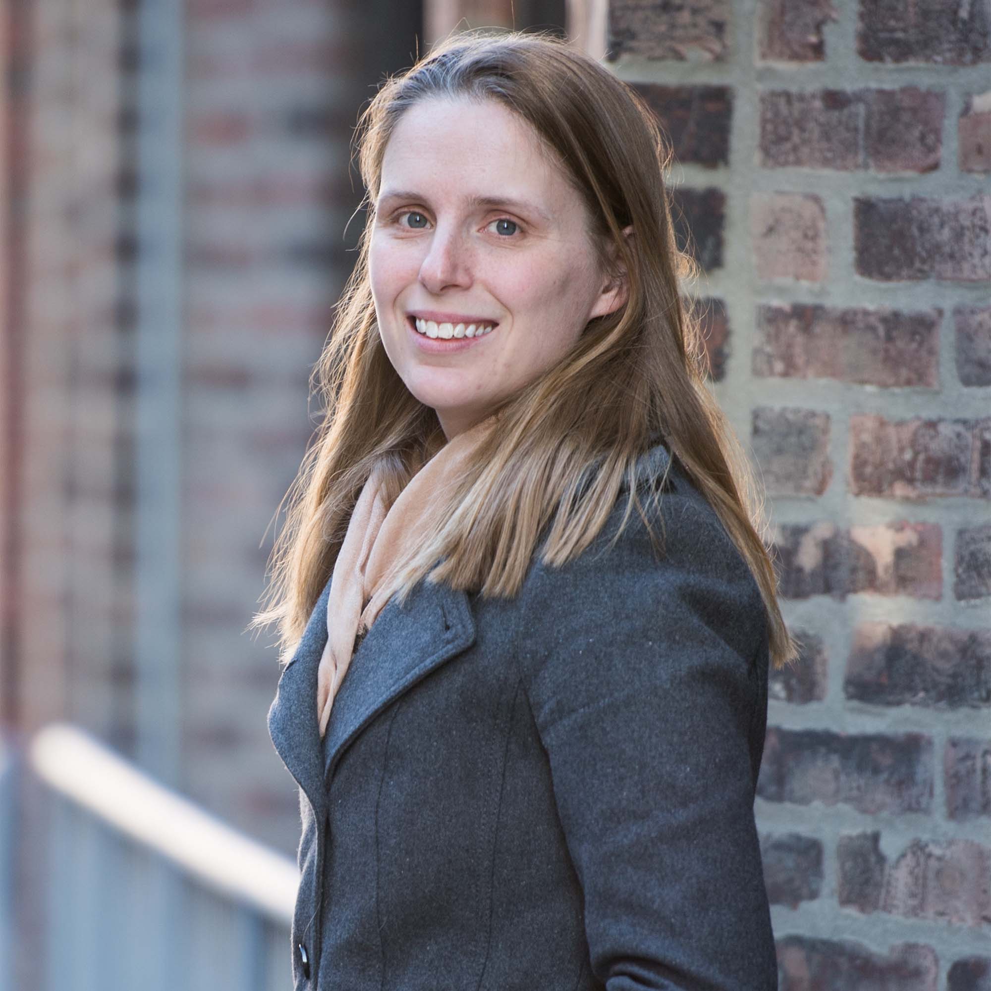 Photo: A white woman smiling for a photo with brown hair and a gray blazer.