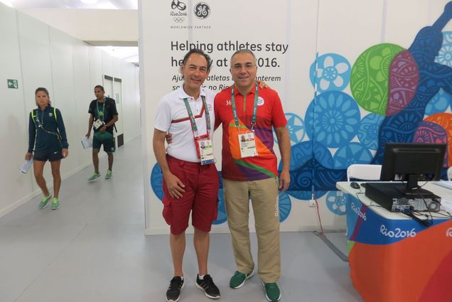 Photo: A picture of two men standing in front of a colorful wall at the Rio 2016 Olympics.