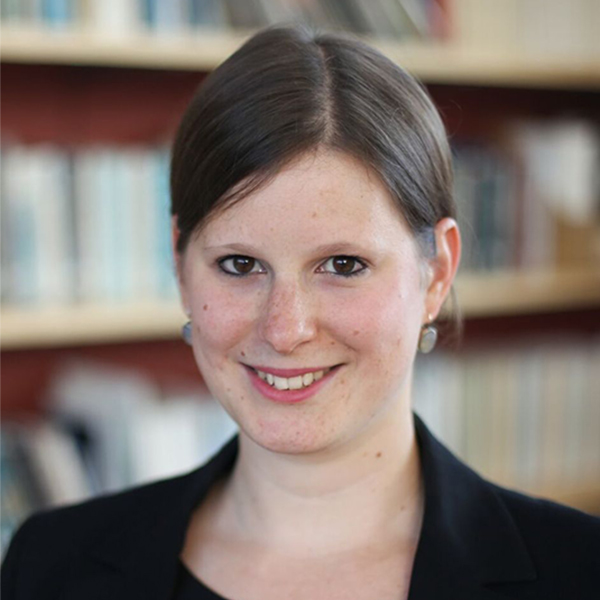 Photo: A woman in a black dress with dark hair smiles for a formal portrait in front of a bookcase