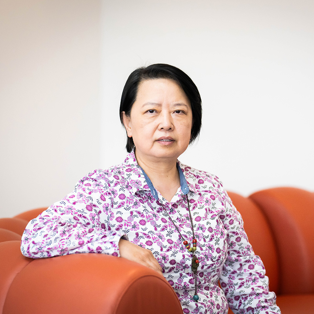 Photo: An Asian woman with short hair poses on an orange couch.