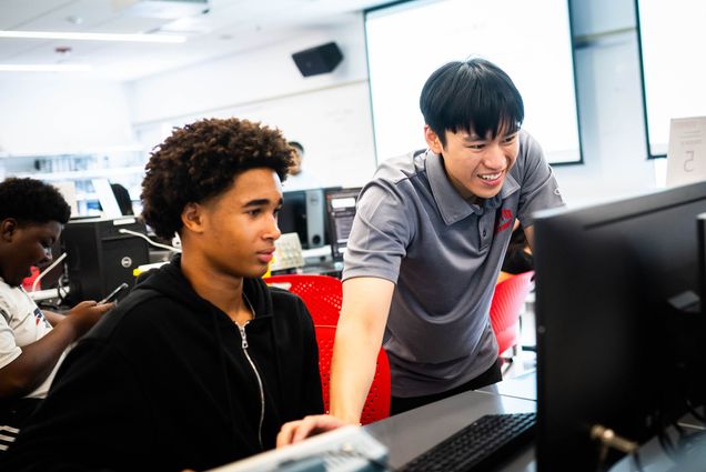 Photo: A picture of two male students l ooking at a computer together.
