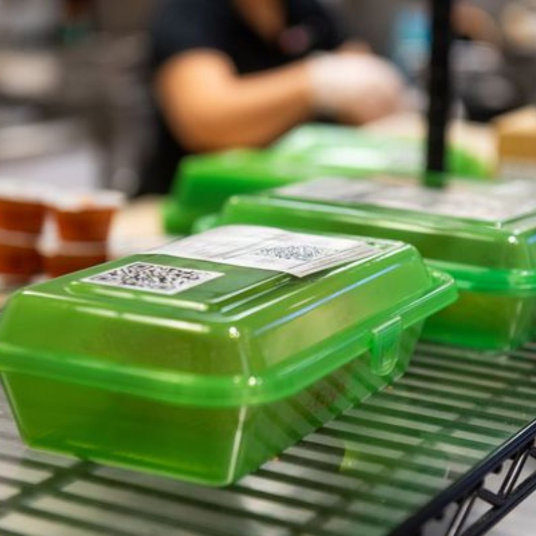 Photo: Clear green to-go containers are shown with orders in them on wire racks. They're each labeled with receipts for what is in the order.