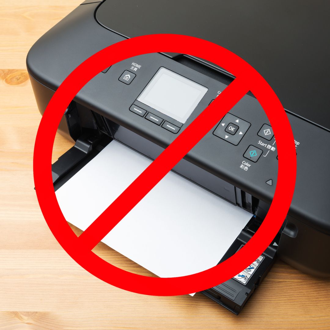 Photo: A close-up of a black inkjet printer with a control panel featuring several buttons and a small display screen, placed on a wooden surface. The printer has a paper tray partially extended with blank paper loaded. Overlaid on the image is a large red prohibition sign, commonly known as a ‘no symbol,’ consisting of a red circle with a diagonal line across it, indicating that something is not allowed or prohibited.