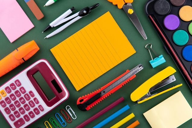 Photo: A stock image flat-lay of various school supplies on a green background.