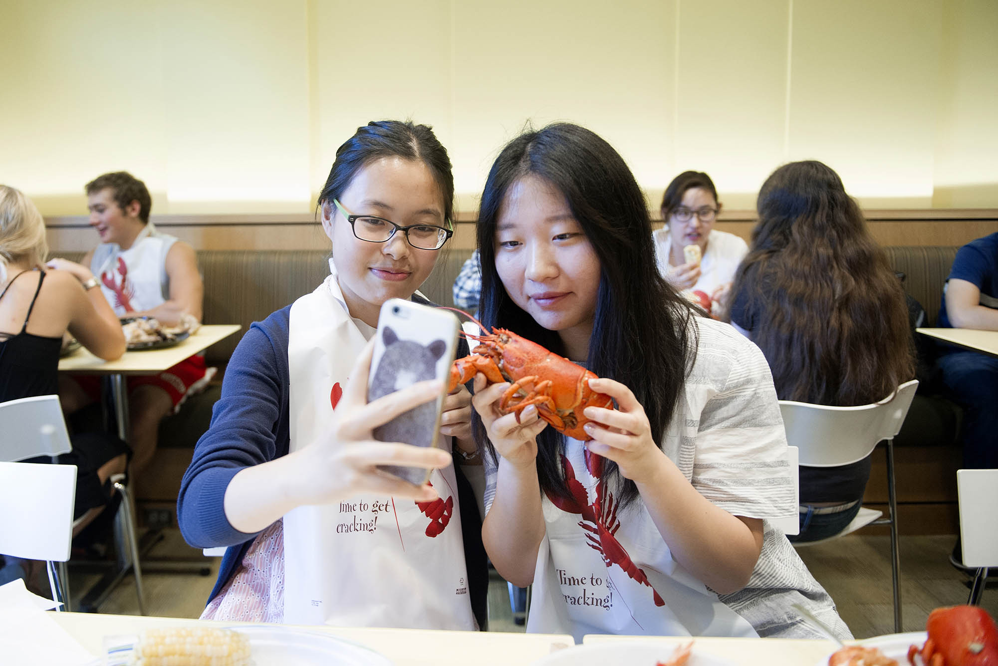 Photo: Sipei Fu (SAR 19) , left and Jie Ling (COM 19) take a selfie with a lobster during lobster night