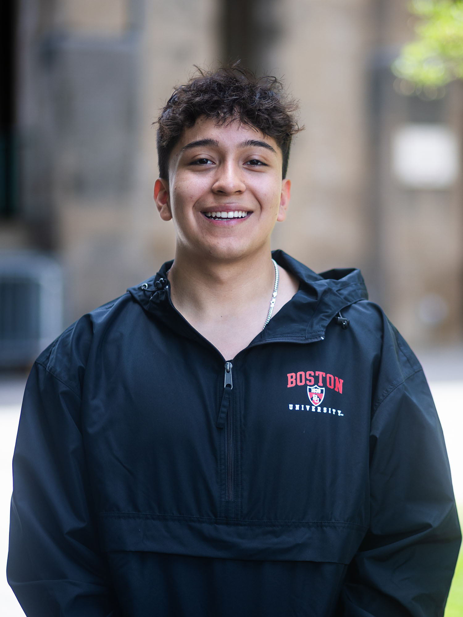Photo: A picture of a young man wearing a black Boston University windbreaker, with the university's logo at the top left in a red font.
