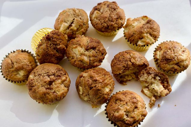 Photo: A picture of muffins in golden tins on a white surface. Some are sitting straight up and others are fallen on their side