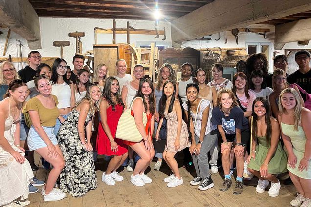 Photo: A large group of college students pose for a group photo. There are 50 or so students in casual clothing posing in front of winery equipment