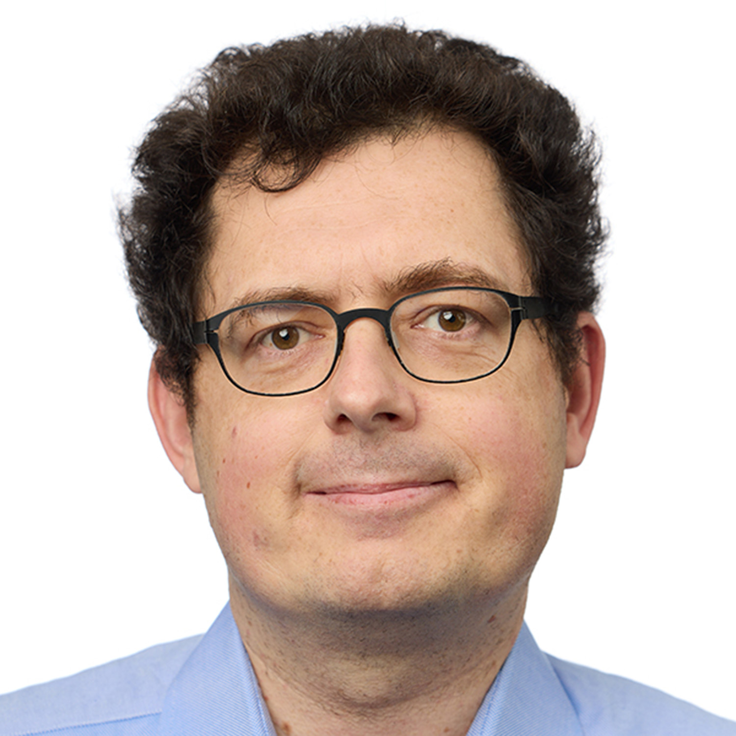 Photo: A headshot of a white man with short, dark hair and dark-framed glasses.