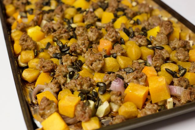 Photo: A close-up of various squash, meat, onions, and shallots on a sheet pan.