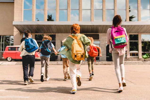 Photo: Schoolchildren running into the school building wearing backpacks.