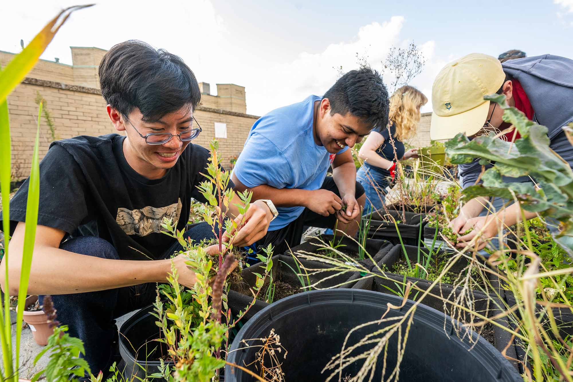 Photo: Two individuals smile as they prune plants.
