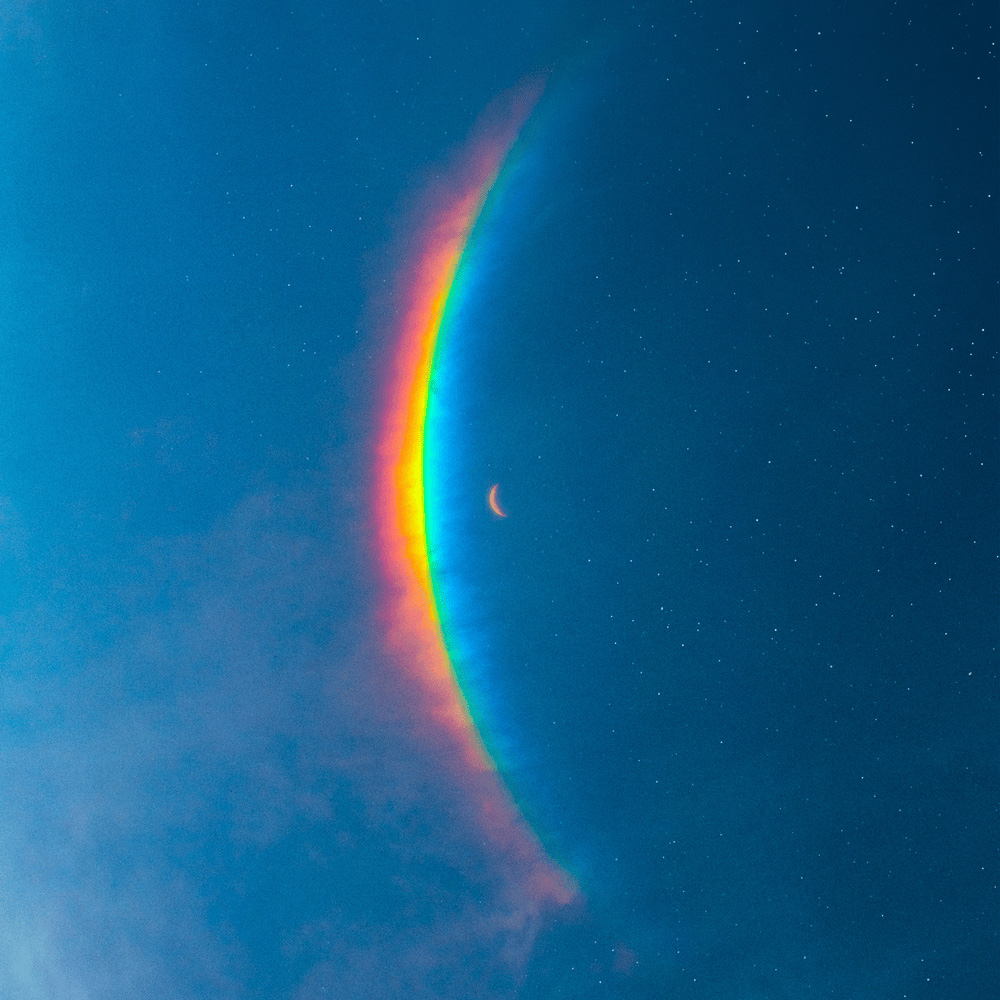 Photo: A blue background with a bent rainbow in the middle of the image.