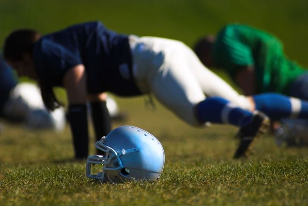 Photo: A football player does a push up on grass next to his helmet