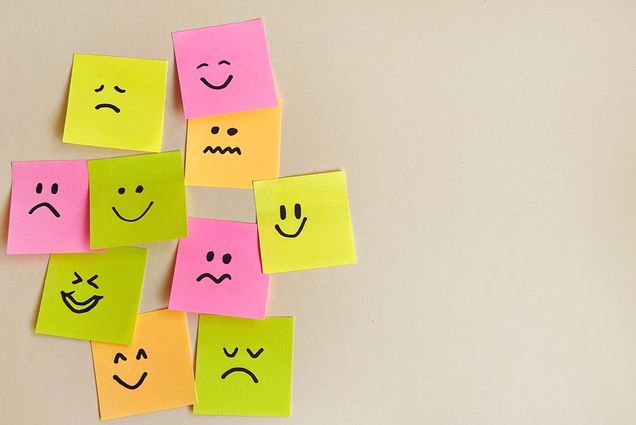 Photo: A picture of colorful sticky notes stuck to a white wall with different facial expressions drawn on them