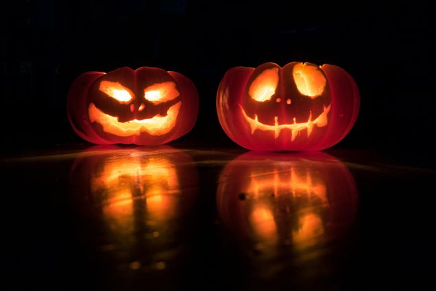 Photo: Two Jack-o-lanterns with creepy, smiling faces sit next to each other, glowing from the inside.