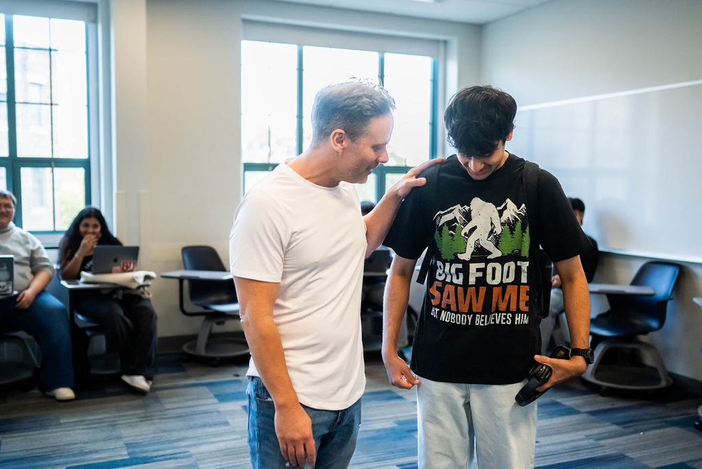 Photo: A man in a white t shirt stands aside a student in a black shirt reading "Bigfoot saw me and nobody believed him"