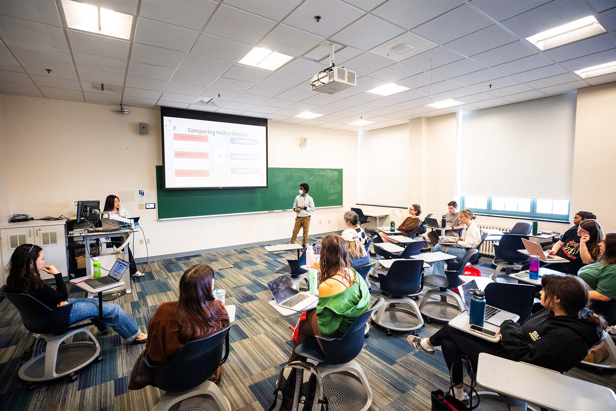 Photo: A full college classroom looking at an electronic screen in a class on Political Science