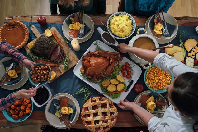 Overhead photo of a thanksgiving dinner table with turkey and many side dishes