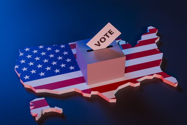 Photo: A Large map of the United States colored in the colors of the american flag, with a ballot box reading "Vote" on top of the map