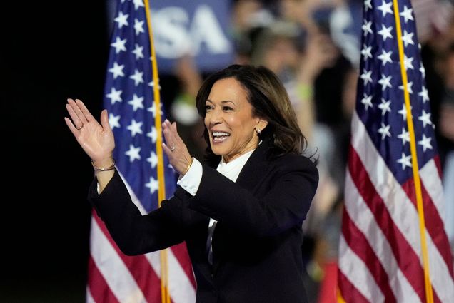 Photo : A picture of Kamala Harris clapping on stage with American flags at a rally