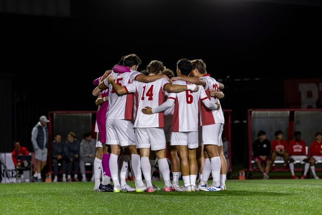 Photo: A picture of a soccer team in red and white uniforms huddling on a field