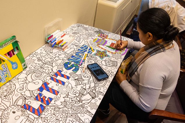Photo: A young woman coloring in a portion of a banner that says "Let it Snow" and features many swirling wintry designs