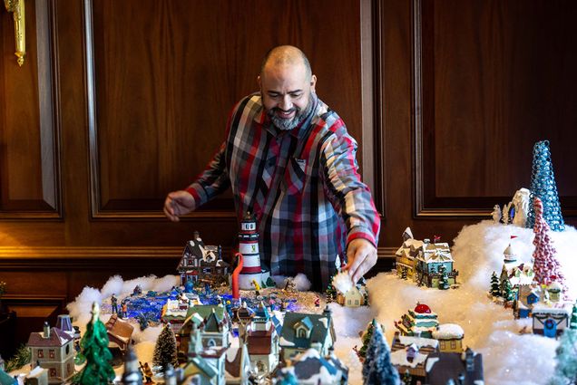 Photo: A man assembling a ceramic winter village