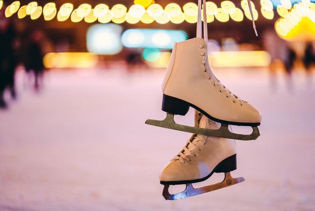 Photo: Ice skates being held up in front of an ice skating rink