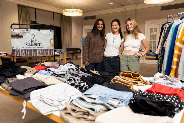 Photo: Three female students posing behind a table full of clothing