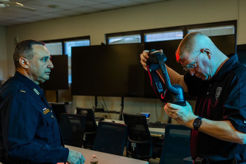 Photo: Two BUPD officers in a room, one is putting on a VR headset