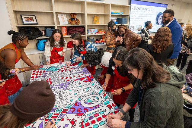 Photo: A group of people coloring on a tablecloth while an event is happening