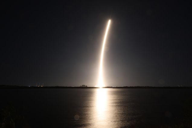 Photo: A rocket blasting off into space over the water.