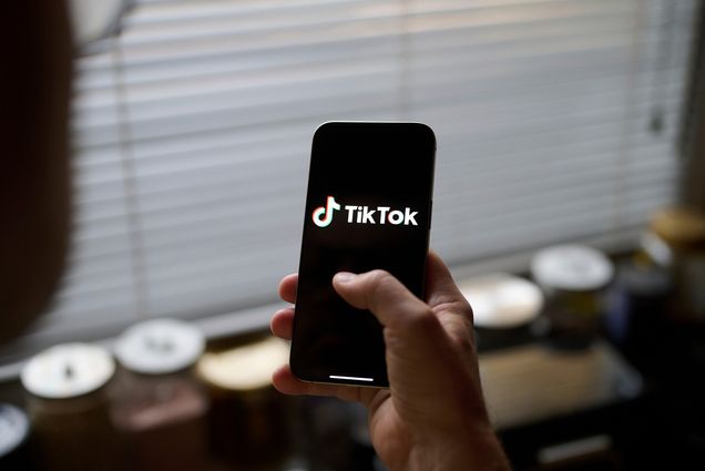 Photo: A person holding a smart phone that has the "TikTok" logo on it