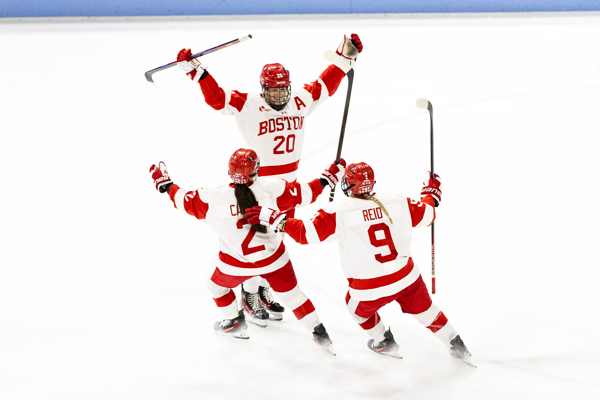 Photo: Three female hockey players in Boston University uniforms celebrating on the ice
