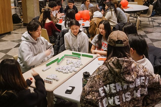 Photo: Students playing mahjong with lanters in the background at a Lunar New Year celebration