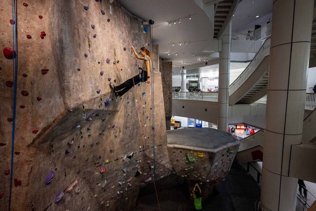 Photo: A wide shot of a rock wall in BU's FitRec Center. A person is climbing the wall, nearing the top.