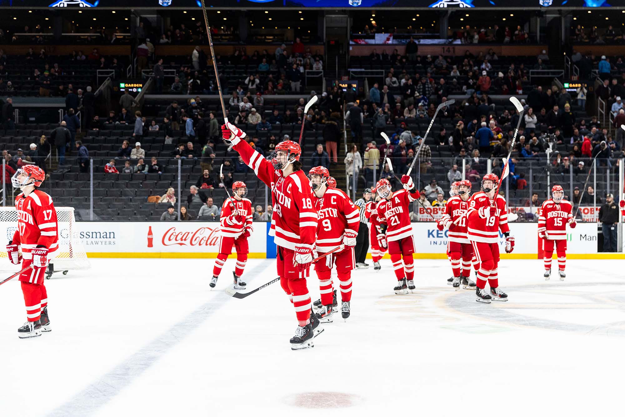 Photo: Boston University hockey players celebrating on the ice with their sticks raised up in the air