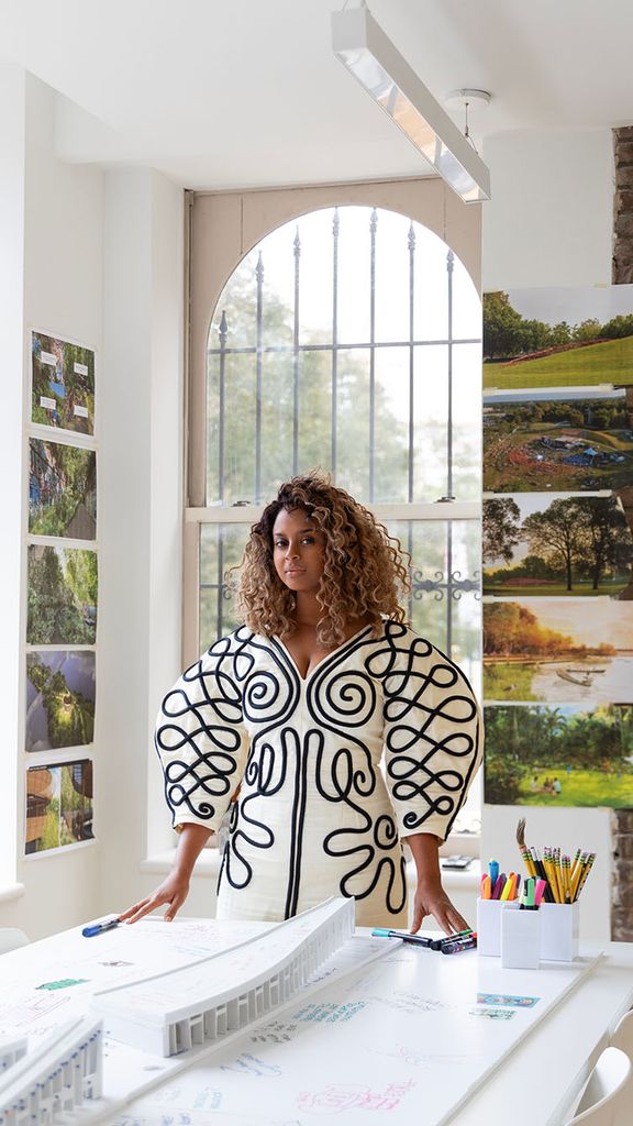 Photo: Sara Zewde a woman with long hair stands in a brightly lit room wearing an elegant and intricately designed outfit with black and white colors