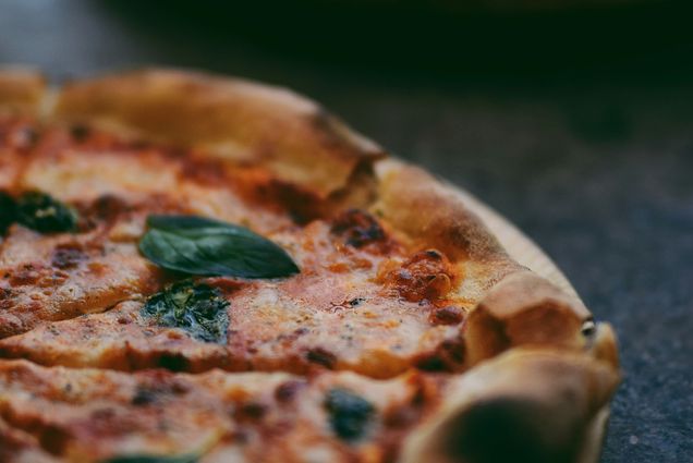 Photo: Upclose of a slice of pizza with basil, tomato sauce, and cheese