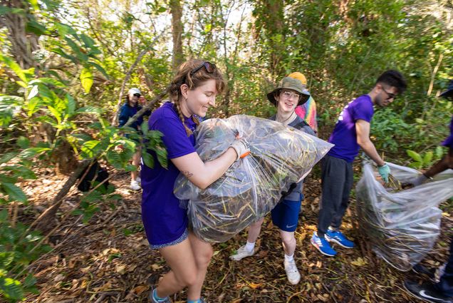 Photo: Students carrying bags of weeds as they dispose of them during an Alternative Service Break trip