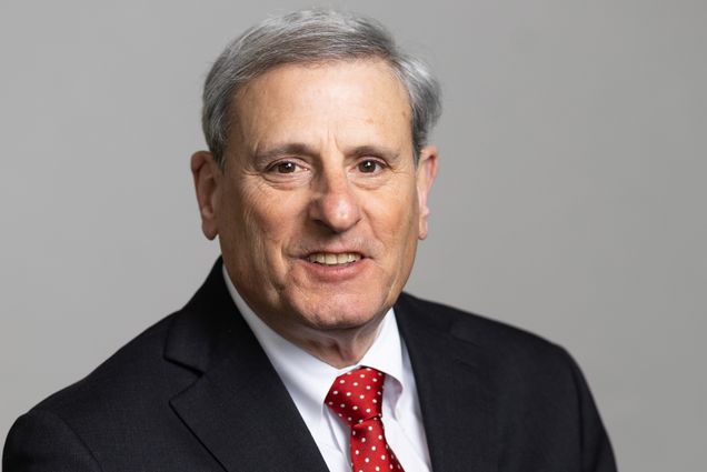 Photo: A man smiling for a portrait while wearing a dark suit and vibrant red tie