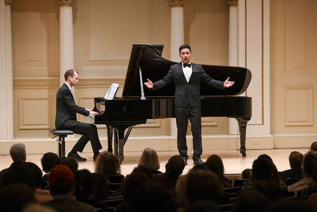 Photo: Two performers in suits on stage at a recital.