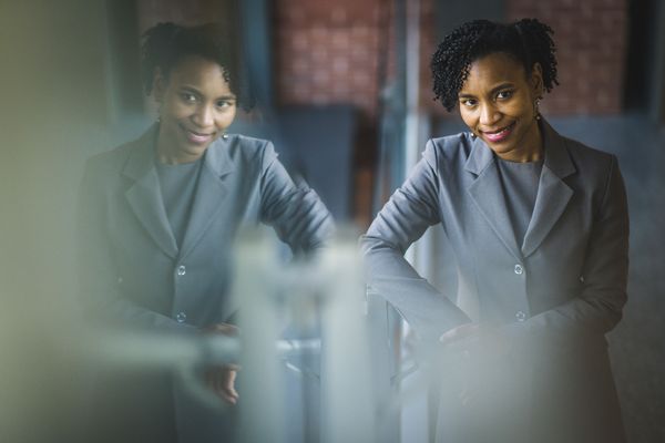 Photo: A woman in a gray suit with curly dark hair poses for a formal portrait