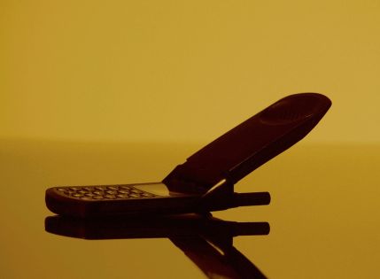 Photo of a flip phone close up in dim yellow-like lighting.